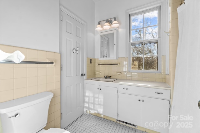 full bathroom featuring tile walls, visible vents, toilet, vanity, and tile patterned floors