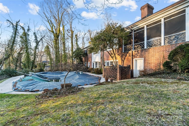 view of swimming pool featuring a yard and a sunroom