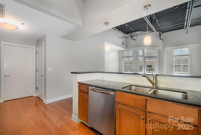 kitchen featuring light wood finished floors, brown cabinetry, dishwasher, hanging light fixtures, and a sink