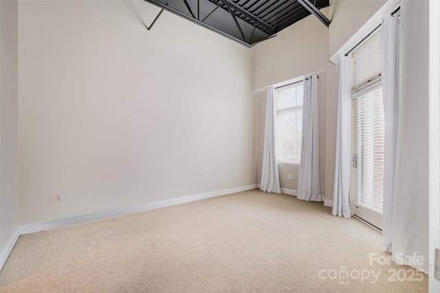 spare room with baseboards and light colored carpet