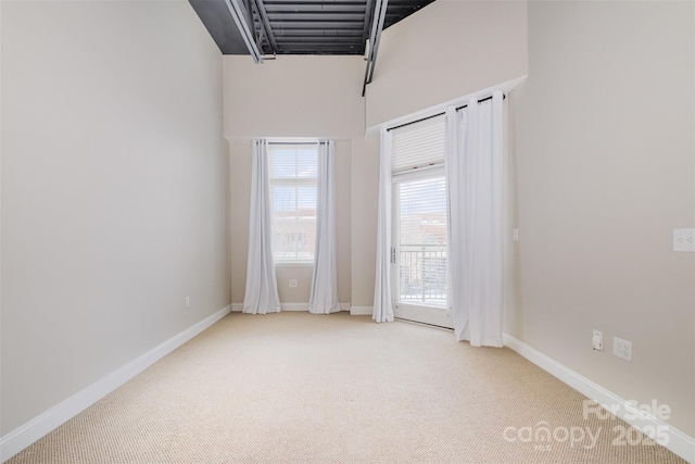 spare room featuring light colored carpet and baseboards