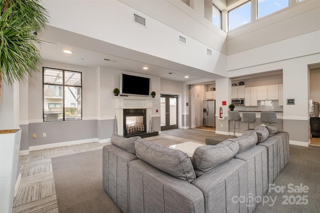 living room featuring a healthy amount of sunlight, visible vents, baseboards, and a multi sided fireplace