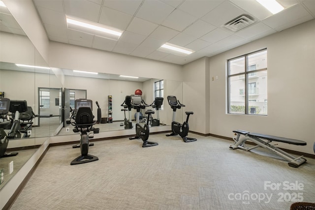 exercise room featuring light colored carpet, visible vents, a paneled ceiling, and baseboards