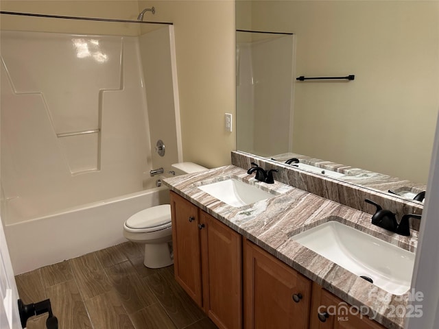 full bath featuring toilet, double vanity, a sink, and bathing tub / shower combination