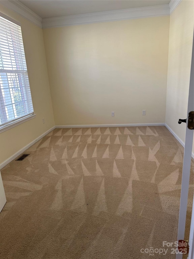 empty room with carpet, visible vents, ornamental molding, and baseboards