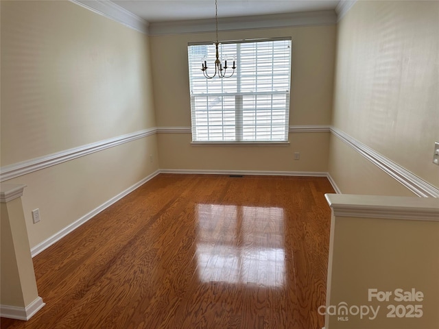 unfurnished dining area featuring crown molding, visible vents, wood finished floors, a chandelier, and baseboards