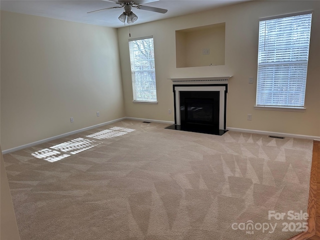 unfurnished living room with a fireplace with flush hearth, light carpet, visible vents, and baseboards