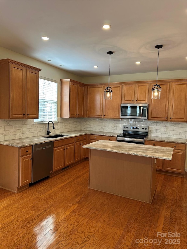 kitchen featuring hanging light fixtures, a kitchen island, stainless steel appliances, and a sink