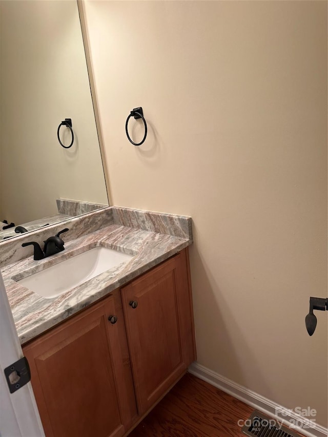 bathroom featuring baseboards, wood finished floors, and vanity