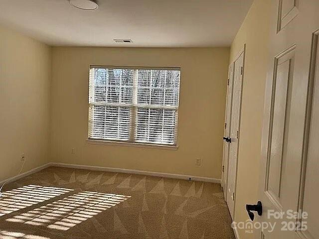 carpeted spare room with visible vents and baseboards