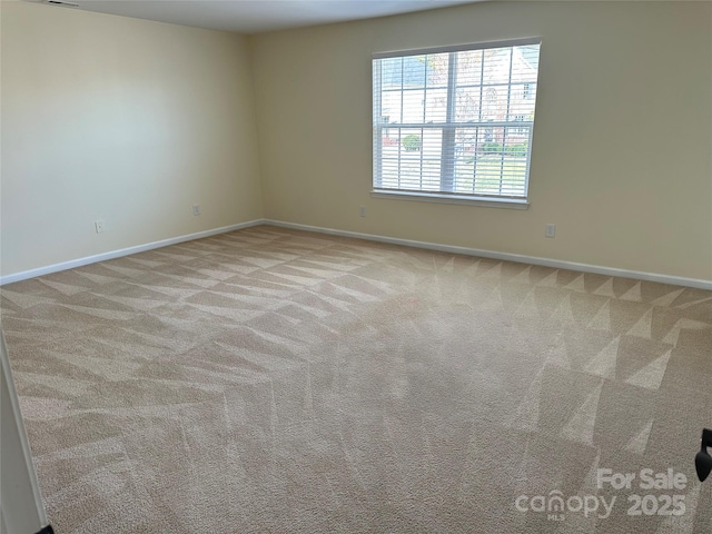 unfurnished room featuring light carpet and baseboards