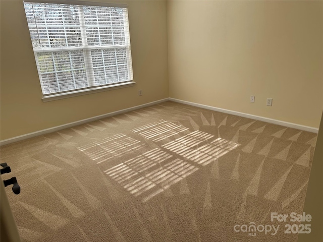 unfurnished room featuring carpet and baseboards