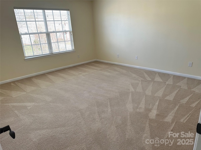 spare room featuring light carpet and baseboards