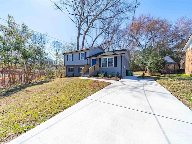 view of front of house featuring concrete driveway, brick siding, fence, and a front lawn