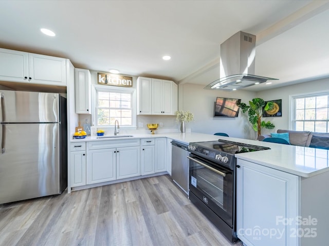 kitchen with stainless steel appliances, light countertops, island exhaust hood, and a peninsula