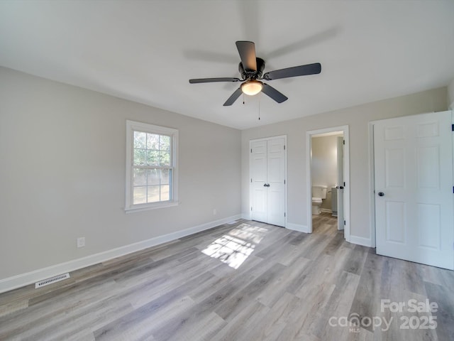 unfurnished bedroom with visible vents, ensuite bathroom, a ceiling fan, light wood-type flooring, and baseboards