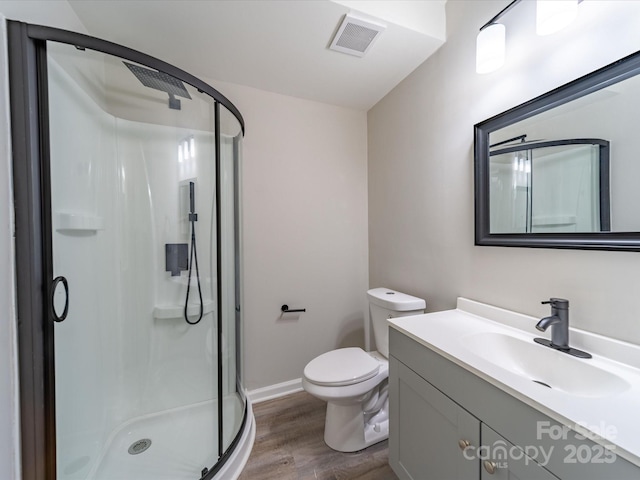 bathroom featuring a stall shower, visible vents, toilet, wood finished floors, and vanity