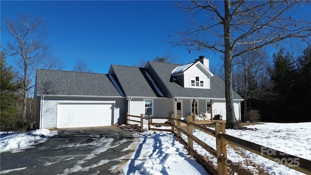 cape cod-style house featuring roof with shingles, driveway, a chimney, and an attached garage