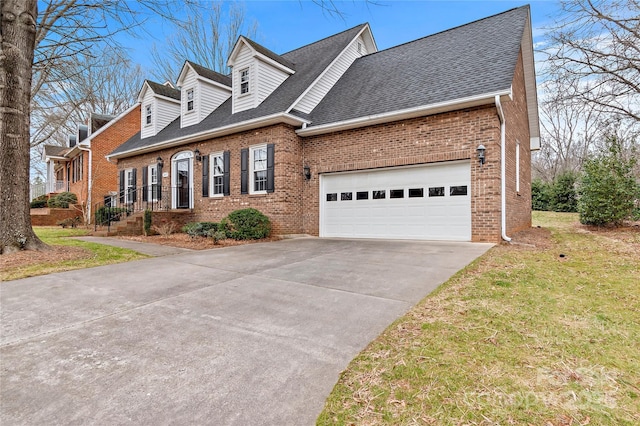 view of front facade featuring driveway, a garage, a shingled roof, brick siding, and a front yard