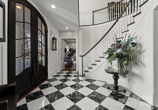 entrance foyer with recessed lighting, french doors, a decorative wall, and stairs