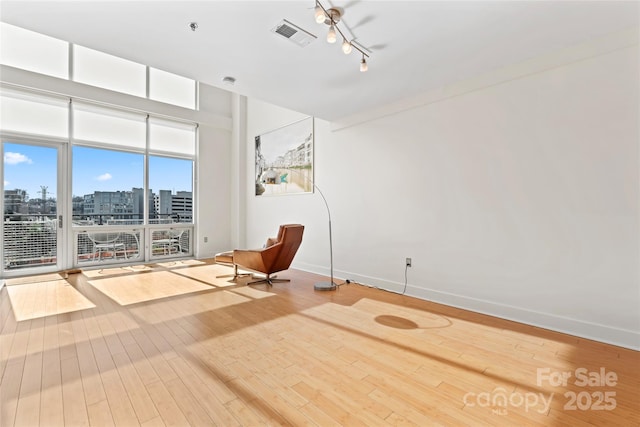 unfurnished room featuring hardwood / wood-style flooring, visible vents, baseboards, a view of city, and rail lighting