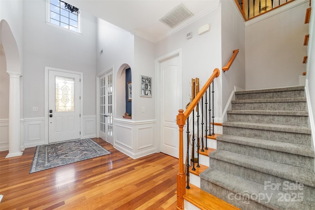 foyer with arched walkways, visible vents, plenty of natural light, and wood finished floors