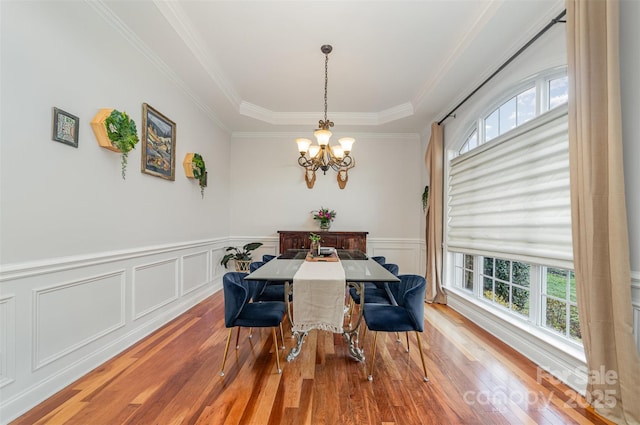 dining area featuring a wealth of natural light, wood-type flooring, crown molding, and an inviting chandelier