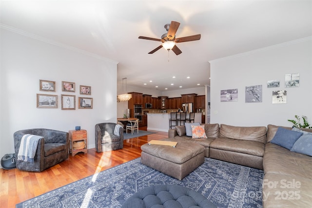 living area featuring recessed lighting, ornamental molding, wood finished floors, baseboards, and ceiling fan with notable chandelier