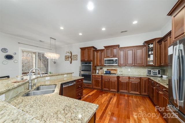 kitchen with a sink, visible vents, appliances with stainless steel finishes, dark wood-style floors, and decorative light fixtures