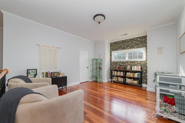 living room with ornamental molding, wood finished floors, visible vents, and baseboards