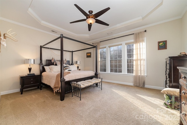 carpeted bedroom featuring ornamental molding, ceiling fan, a tray ceiling, and baseboards