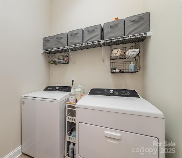 washroom featuring laundry area, baseboards, and washer and clothes dryer