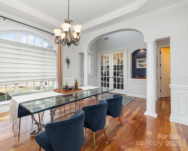 dining room with hardwood / wood-style flooring, decorative columns, arched walkways, and french doors