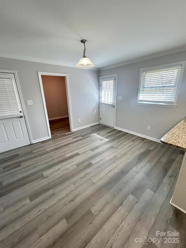 unfurnished dining area with ornamental molding, wood finished floors, and baseboards