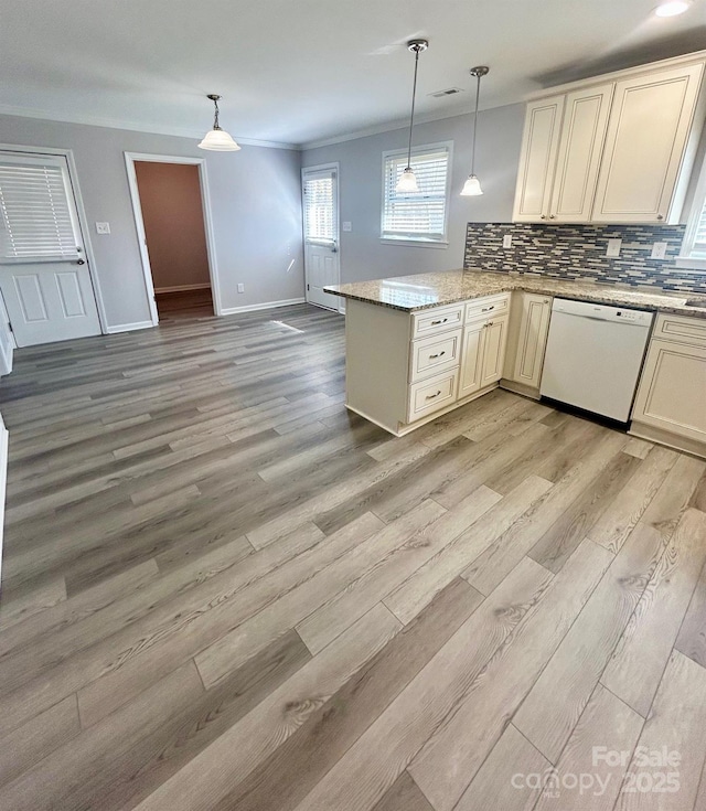 kitchen featuring pendant lighting, tasteful backsplash, light wood-style flooring, dishwasher, and a peninsula