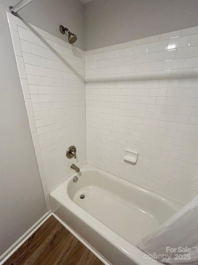 full bath with shower / washtub combination, wood finished floors, and baseboards