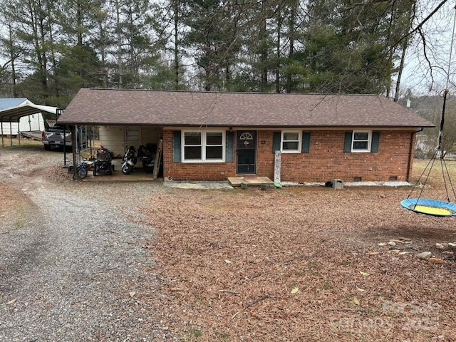 ranch-style house with gravel driveway, brick siding, roof with shingles, crawl space, and a carport