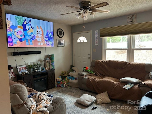 living room featuring a ceiling fan and a textured ceiling