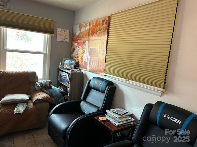 living area with a textured ceiling and tile patterned floors