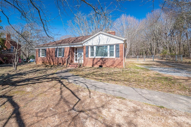 view of front of property with driveway, a chimney, crawl space, fence, and brick siding