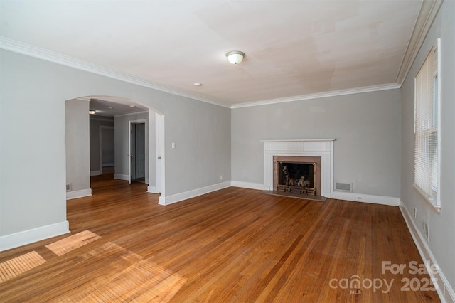 unfurnished living room with a fireplace with flush hearth, arched walkways, visible vents, and wood finished floors