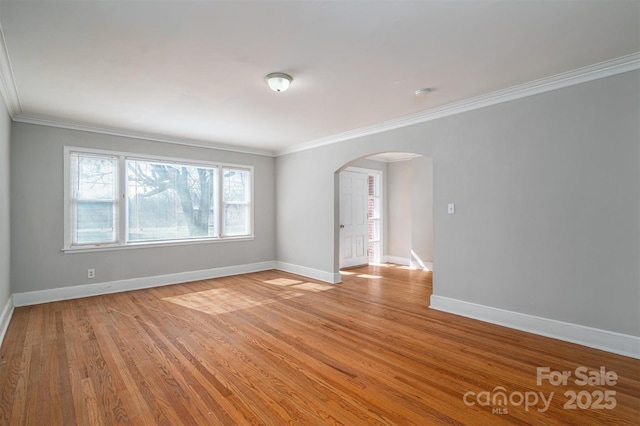 unfurnished room featuring light wood-style floors, baseboards, arched walkways, and ornamental molding