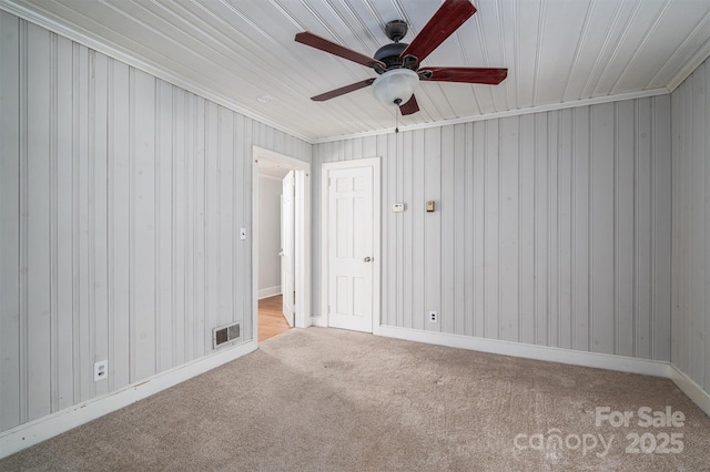 spare room with light carpet, ceiling fan, visible vents, and baseboards