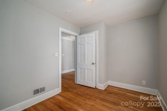 spare room with light wood-type flooring, visible vents, and baseboards