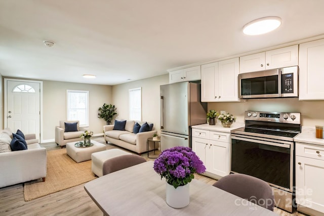 kitchen with open floor plan, light countertops, appliances with stainless steel finishes, and white cabinets