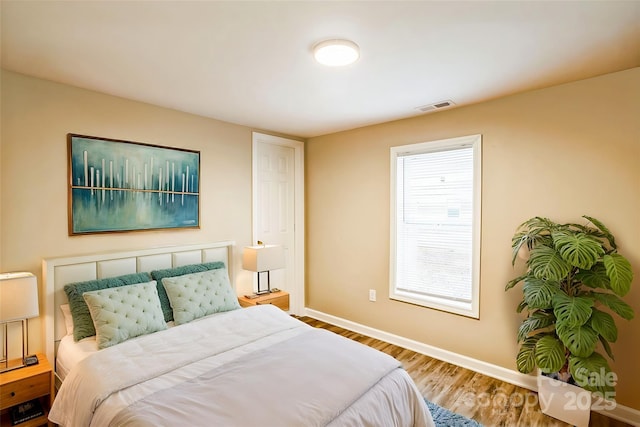 bedroom with wood finished floors, visible vents, and baseboards