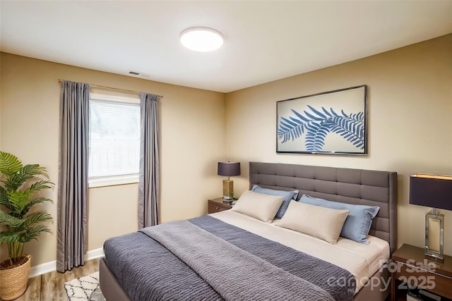 bedroom featuring baseboards, visible vents, and light wood finished floors