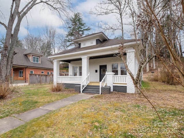 bungalow featuring a front yard, covered porch, and brick siding