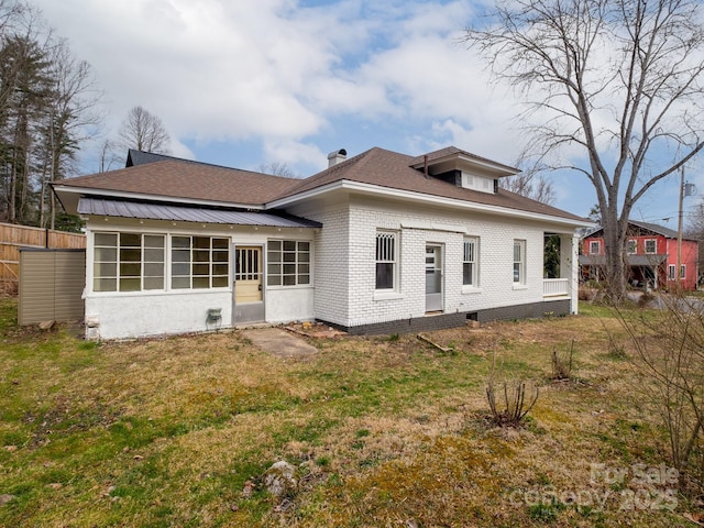 back of house with brick siding, a lawn, and fence