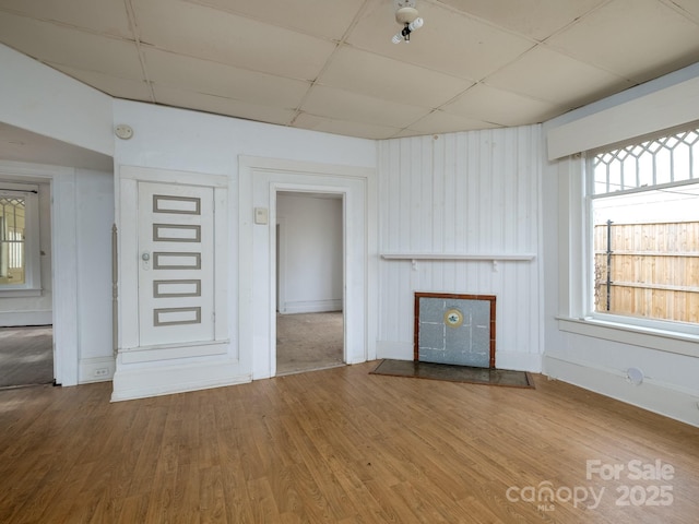 unfurnished living room featuring a paneled ceiling, a fireplace, and wood finished floors